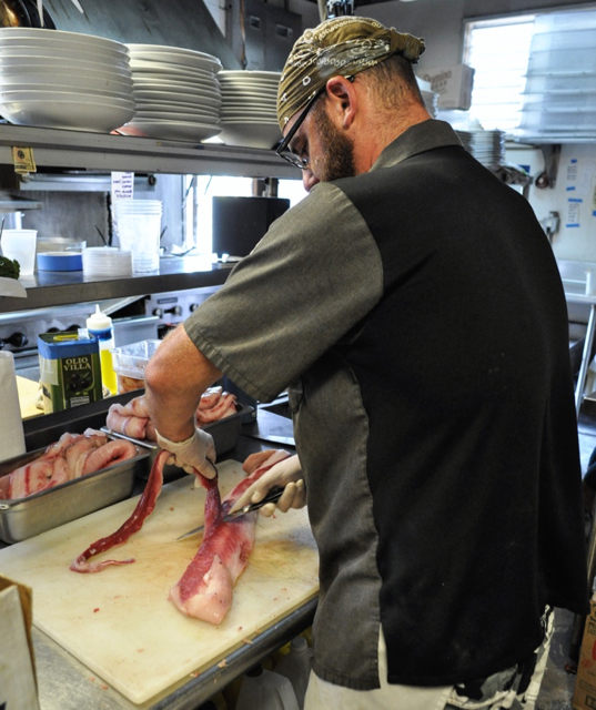 Extra Virgin Bistro chef and co-owner Tom Garfield preps some local mahi mahi before the restaurant opens. 