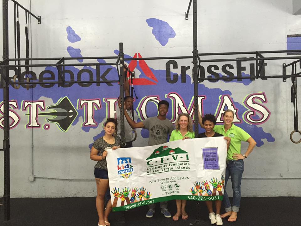 Crossfit St. Thomas volunteers help to distribute books to young children.