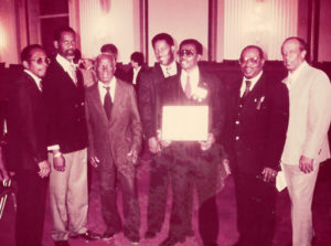 McIntosh receives an award from the National Endowment of the Arts with band members Meg Gordon, Isidore Griles, Frank Charles, Lloyd Thomas, Sylvester “Blinky” McIntosh, Anselmo Clarke and Gustave Petersen.