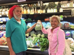 Starfish Market produce clerk Leslie Lambertis and Josephine Roller put a fresh bag of St. John-grown greens on the shelf.