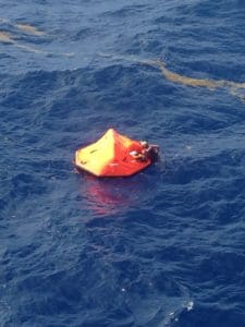 A Coast Guard rescue swimmer grabs hold of a life raft Thursday about 32 miles south of St. Croix. The helicopter crew rescued two people who had abandoned their sinking vessel. (Coast Guard photo)