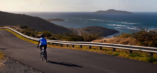 A cyclist rides the road down from Point Udall, with Buck Island in the background. (File photo)