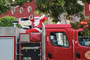 Santa arrives for the Miracle on Main Street riding a red-nosed fire truck.
