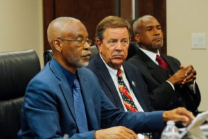 From left, EDC Board Chairman Jose Penn, Vice Chairman Philip Payne and EDA CEO Kamal Latham listen to testifiers during Tuesday’s show of cause hearing.