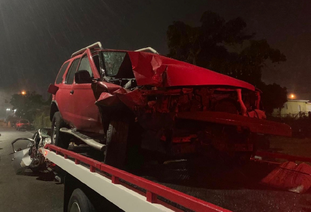 A mangled red Nissan sedan is loaded onto a tow truck. It was struck by the damaged silver Toyota Yaris seen in the background. (VIPD photo)