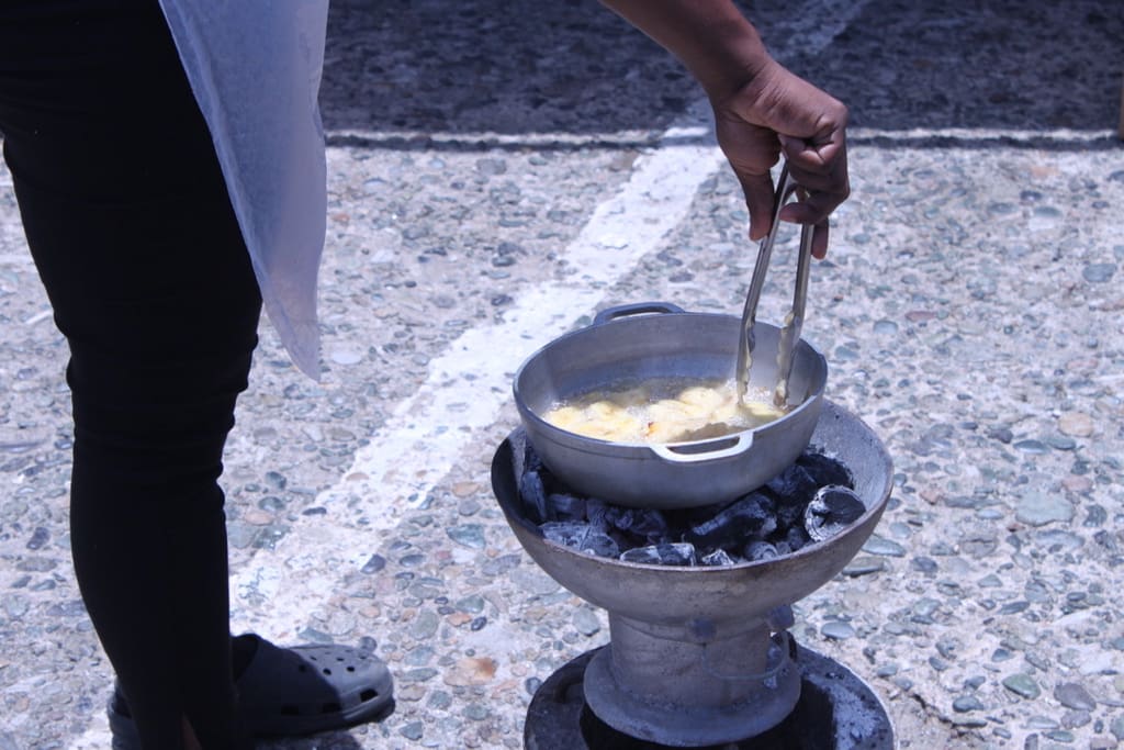 Officer George stirs bananas sizzling in a coal pot while helping assist students representing Lockhart Elementary. While the team wanted plantains, George said bananas would have to do as plantains were unavailable. (Bethaney Lee photo)