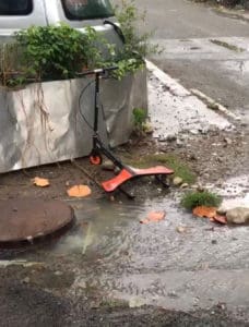 A scooter rests near an overflowing manhole near Pond Mouth.