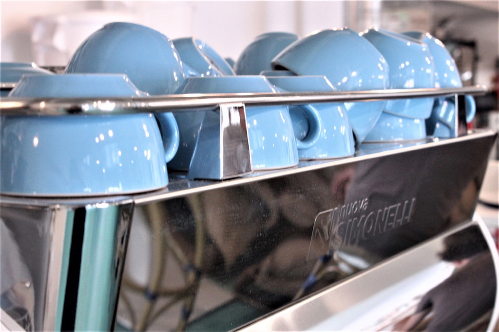 A rack full of blue mugs sits ready to be used by employees who create handcrafted brews for customers.