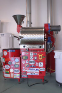The roasting machine sits to the right of the coffee shop and is used to bring out the flavors and characteristics of the various coffee beans.
