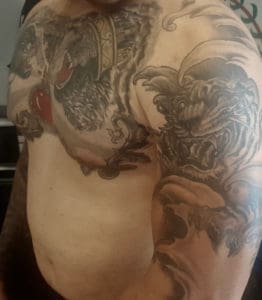 A customer displays his tattooed upper chest and arm. (Source photo by Denise Lenhardt-Benoit)