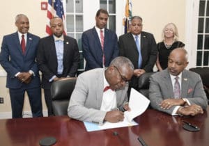 Gov. Albert Bryan, Jr. signs into law new amendments to the territory’s Hotel Development Act during a ceremony Monday. Joining him were: Lt. Gov. Tregenza Roach, Finance Commissioner Kirk Callwood Sr., Tourism Commissioner Joseph Boschulte, Chief Executive Officer of the Economic Development Authority Kamal Latham, Senator Kurt Vialet and President of the Hotel and Tourism Association, Lisa Hamilton. (Photo submitted by Government House)