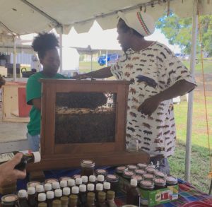 Beekeeper Roniel Allembert talks about bees in his observation hive. (Source photo by Susan Ellis)