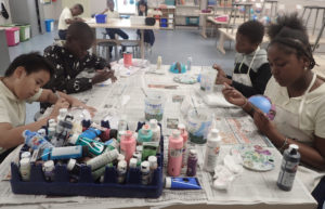 Students at Arthur Richards School paint holiday ornaments. Front table from left: Christian Diaz, 11, Rajun Charles, 11, Jesse Quilden, 10, and Tinye Isaac, 11. Back table: Caden Guirty, 10, Tahjai Young, 9, Cayla Diaz, 9. (Source photo by Susan Ellis)