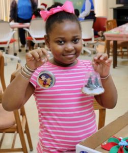 Jordin Jackson holds her two favorite Christmas ornaments from an afternoon of artistic fun. (Source photo by Linda Morland)