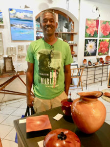 Avelino stands behind some of his carved bowls. (Source photo by Amy Roberts)