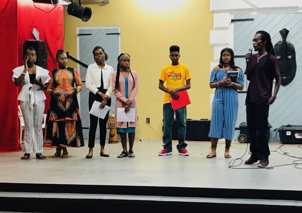 St. Croix Central High ninth graders, from left, Angelina Valentine, Elicia Wattley, Bry'nice Berley, Jedaya George, Anwar Mohammad, Quishylah Navaro, and their teacher Geron Richards read their own poetry drawn from their knowledge of their history and culture. (Source photo by Elisa McKay)