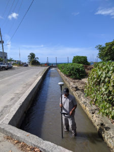 Greg Guannel, director of UVI’s Caribbean Green Technology Center, measures sediment depth in the gut that empties near the seaplane terminal in Christiansted. (Photo submitted by Hilary Lohmann, DPNR)