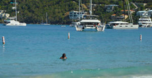 A local woman takes a sea bath in shadow of yachts Sunday. (Source photo by S. Pennington)