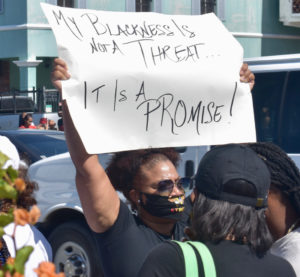 A protester holds up a sign Saturday that reads 'My Blackness Not A Threat, It's a Promise." (Source photo by Kyle Murphy)