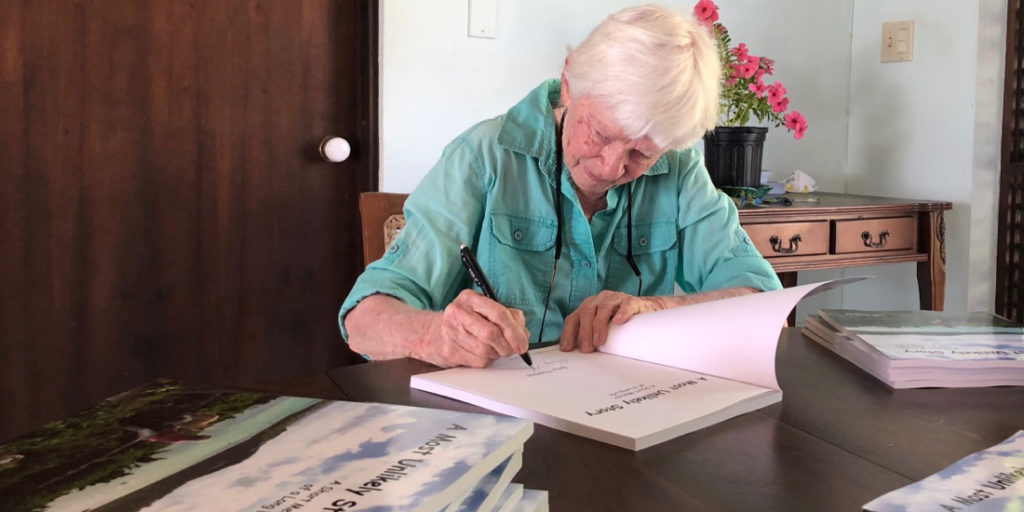 Author and painter Emy Thomas signs copies of her new book. “A Most Unlikely Story.” (Source photo by Susan Ellis)