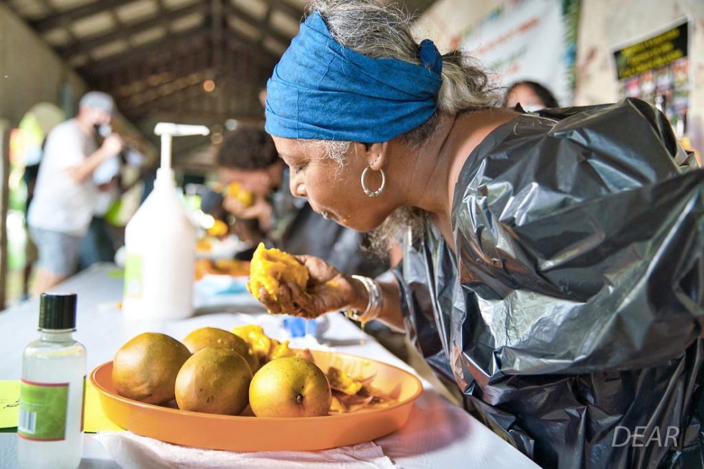 With her left hand behind her back, this mango-eating contestant dives into the plate of tropical fruit. (Photo provided by DEAR Productions Photography)