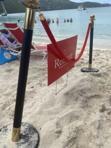 A velvet rope and "retreat" sign designate an area of Magens Bay Beach reserved for customers renting beach chairs. (Photo by Jason Budsan)