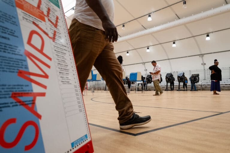 Voting center judge Daniel Sierra, center, and facilitator Beatrice Hoyer, right, keep things running smoothly on Tuesday morning in the St. Croix Central High School gymnasium on St. Croix. (Source photo by Kit MacAvoy)