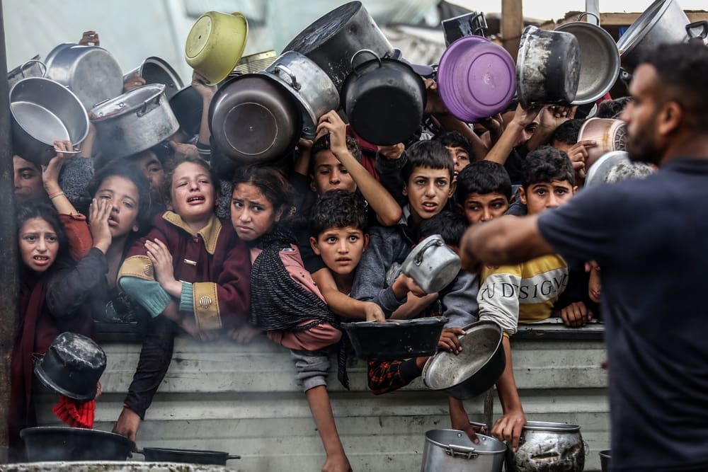 Displaced Palestinians in Al-Mawasi crowd to get rice meals due to the lack of flour and also the lack of entry of aid, in the southern Gaza Strip, on Nov. 29. (Shutterstock photo by Anas-Mohammed)